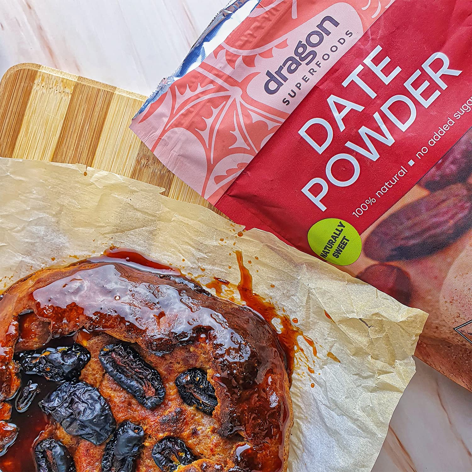 Bag of Dragon Superfoods date powder next to a dessert with dates on a wooden board.