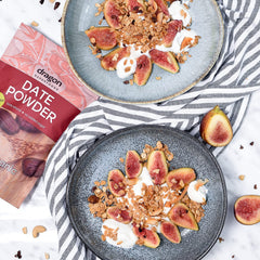 Two plates of granola with figs and yogurt, next to a box of date powder.