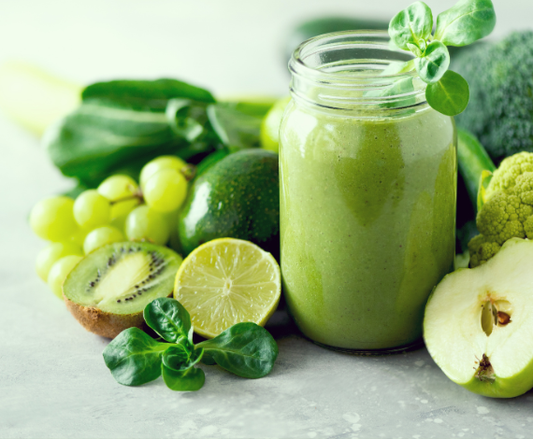 A healthy green smoothie made with Moringa powder surrounded by fresh green fruits like lime, kiwi, and apples.