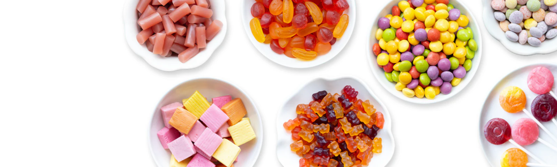 Top-down view of colorful Yum Earth organic candies and gummies in small white bowls, perfect for wholesome snacking.