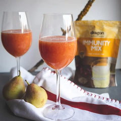 Two glasses of red juice with pears and an 'Immunity Mix' package in the background.