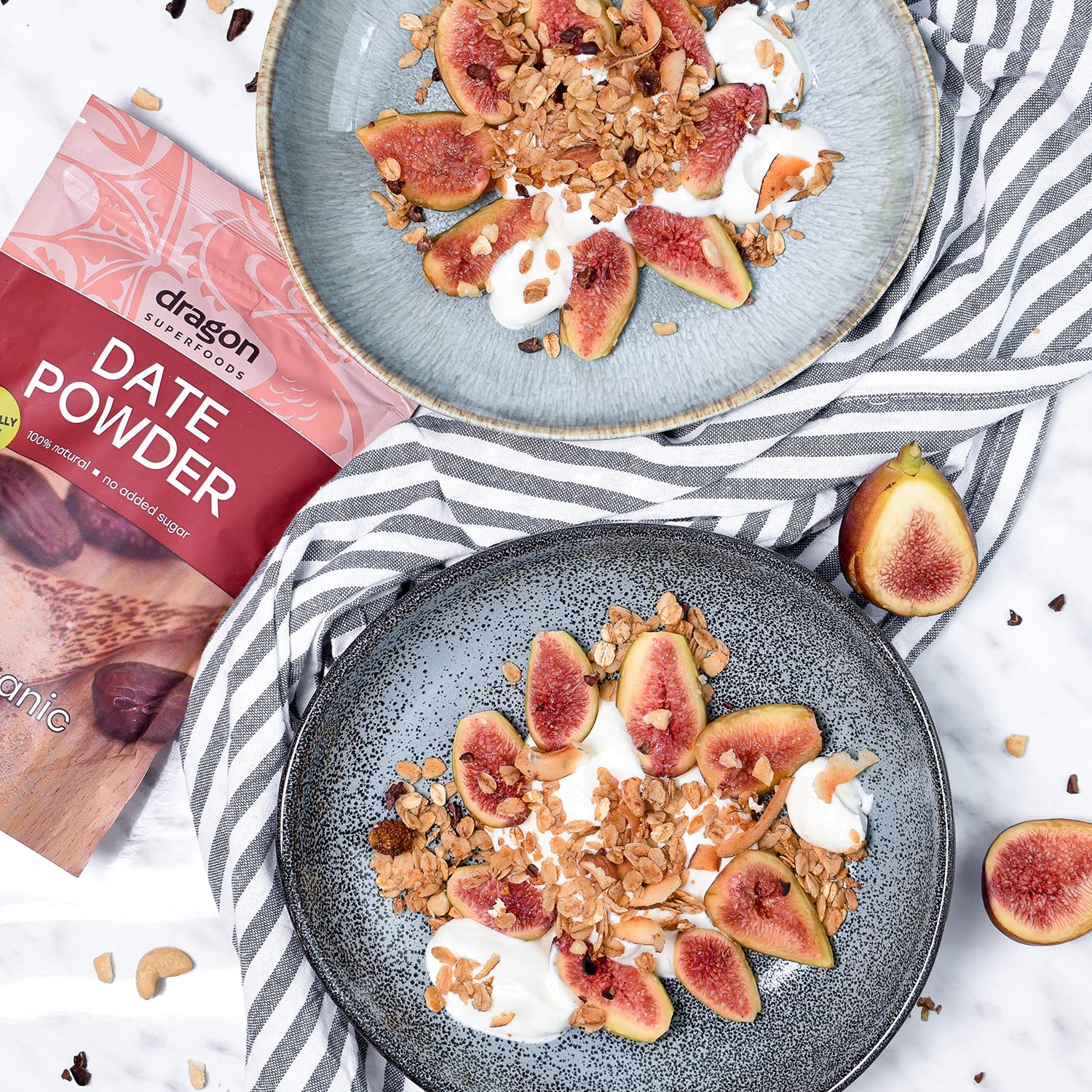 Two plates of granola with figs and yogurt, next to a box of date powder.